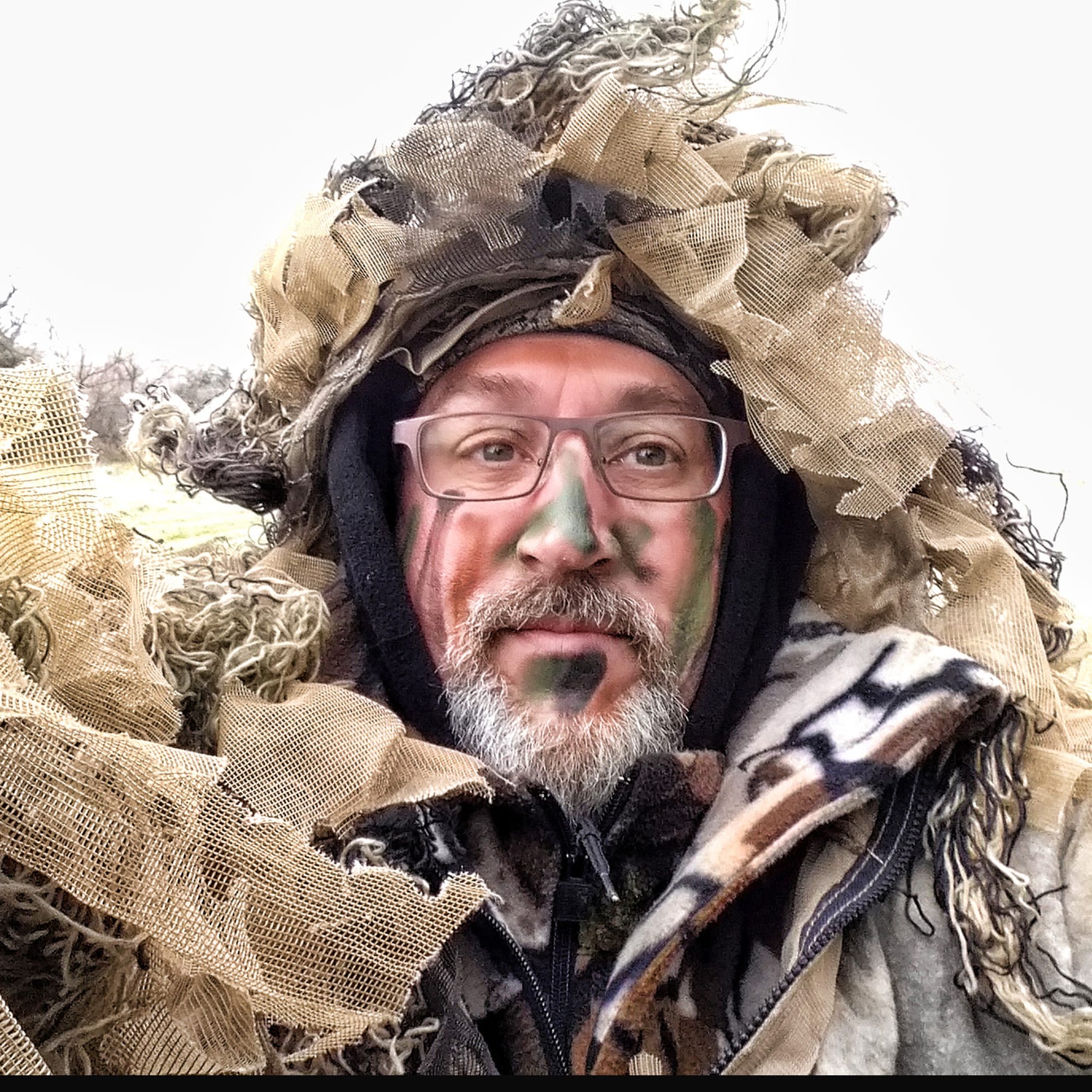 hunter with camo paint on his face in a ghillie suit